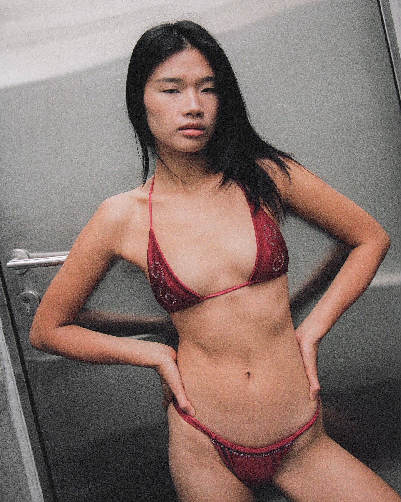 Woman wearing a maroon sequin bikini in a bathroom setting.